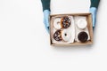 Work of fast food restaurant during virus epidemic. Waiter gives box with donuts with white and chocolate glazed and