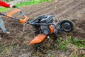 Work on the field of a home farm. Plowing the garden with a cultivator or tiller.Cultivator cutters entangled in weeds Royalty Free Stock Photo
