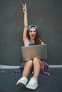 Work follows her wherever she goes. a cheerful young woman working on a laptop while raising her hand and being seated Royalty Free Stock Photo