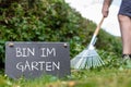 Work in the garden. Man is raking leaves of a freshly cut hornbeam hedge. The German sentence Royalty Free Stock Photo