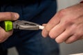 Work with green pliers and a white cable. Hands in the frame. Close-up. Horizontal orientation. Royalty Free Stock Photo