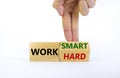 Work hard or smart symbol. Businessman turns wooden block and changes words `work hard` to `work smart`. Beautiful white