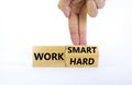 Work hard or smart symbol. Businessman turns wooden block and changes words `work hard` to `work smart`. Beautiful white