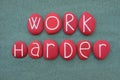 Work Harder, creative and motivational slogan composed with red colored stone letters composed over green sand