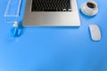 Work from home concept. Laptop, black coffee. mouse, medical face mask, Blue alcohol hand sanitizer gel on blue background with