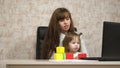 Work at home. in the room, mom works at the table with her little daughter at the computer. business woman working in Royalty Free Stock Photo