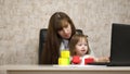 Work at home. in the room, mom works at the table with her little daughter at the computer. business woman working in Royalty Free Stock Photo