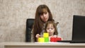 Work at home. in the room, mom works at the table with her little daughter at the computer. business woman working in Royalty Free Stock Photo