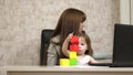 Work at home. in the room, mom works at the table with her little daughter at the computer. business woman working in Royalty Free Stock Photo