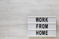 `Work from Home` words on a lightbox on a white wooden background, top view. Overhead, from above, flat lay. Space for text