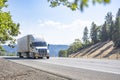 Work horse big rig semi truck transporting cargo in loaded refrigerator semi trailer driving on the mountain highway road in Royalty Free Stock Photo