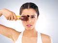 They work just like magic. Studio portrait of a beautiful young woman holding up makeup brushes against her face against