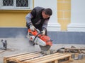 Work on laying the new tile on a city street. Lays the new tile on the floor. Paving in the city. Worker sawing the tiles. Russia.