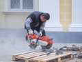 Work on laying the new tile on a city street. Lays the new tile on the floor. Paving in the city. Worker sawing the tiles. Russia.