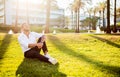 Work life balance concept. Happy young european businessman sitting on grass in park, having break and resting, free Royalty Free Stock Photo