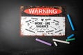 Work Life balance concept. Metal warning sign and colored pieces of chalk on a dark chalkboard background Royalty Free Stock Photo