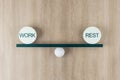 Work life balance concept with scales from board on a ball and equal weight plates with words work and rest on wooden background Royalty Free Stock Photo