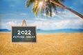 2022 future ahead on chalkboard with coconut palm tree on tropical beach with cloudy sky background Royalty Free Stock Photo