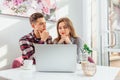 Young business people working together in cafe, using laptop, woman is concentrated on work but man is looking at her Royalty Free Stock Photo