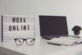 WORK ONLINE sign and laptop with blank screen on desk at home office, mockup for design. Freelancer or blogger workplace Royalty Free Stock Photo