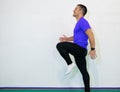 Work out. Young caucasian male athlete sprinter running, exercising indoors, jogging in training room, side view. Orange shirt and Royalty Free Stock Photo