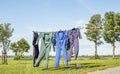 Laundry drying, work overalls hang on the line of the laundry rack with the clothes peg basket on a sunny summer day Royalty Free Stock Photo