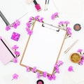 Work place with clipboard, pastel flowers, cosmetics and accessories on white background. Flat lay, top view. Freelancer concept Royalty Free Stock Photo