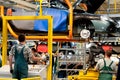 Work at the plant assembles the vehicle using a lift