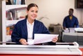 Work in printing house - woman cuts paper with professional cutter