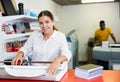 Work in printing house - woman cuts paper with professional cutter