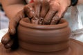 Female or male hands form a bowl on a spinning pottery wheel. Work with red clay. Traditional hand made dishes. Shallow depth of Royalty Free Stock Photo