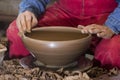 Work with red clay. Male hands form a bowl on a spinning pottery wheel.