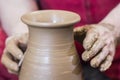 Work with red clay. Male hands form a bowl on a spinning pottery wheel. Royalty Free Stock Photo