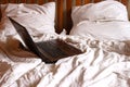 Laptop in unmade bed on background of grey crumpled sheets and pillows. Home office concept