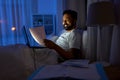 indian man with laptop and papers in bed at night Royalty Free Stock Photo