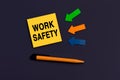 The Work safety message on card for presentation, business. Orange square sticky note, near pen and colourful arrows on dark