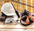 Work safety protection equipment. Industrial protective gear on wooden table, blur construction site background Royalty Free Stock Photo