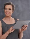 Work smarter, not harder. A mature businesswoman looking thoughtful while holding her digital tablet.