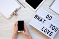 Work space with tablet, female hands, smartphone, clipboard and `Do what you love` word on modern board over white wooden backgr