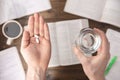 Work stress concept. Hands holding pills and glass of water above Workspace desk with pharmaceutical pills Royalty Free Stock Photo