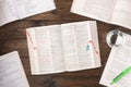 Work stress concept. Workspace desk with pharmaceutical pills, books, pen, paper, and glass of water on wooden background