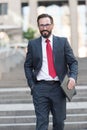 Work on the tablet. Businessman is walking down the street holding mini tablet in hand. Portrait of happy confident businessman