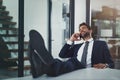 Work it tim you win it. a handsome young businessman relaxing with his feet up on an office desk while using his phone. Royalty Free Stock Photo