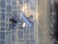 Work tools lie on the surface of gray paving slabs and concrete screed along the edge, top view. White rubber mallet and metal