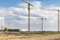 The work of tower cranes against the background of the sunset sky. Modern housing construction. Industrial engineering. Royalty Free Stock Photo