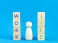 Work versus life concept. Wooden cubes and doll against blue background. Royalty Free Stock Photo