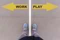 Work vs Play text arrows on asphalt ground, feet and shoes on fl