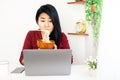 Workaholic Asian business woman busy and overworked on laptop and eating noodles at home office desk Royalty Free Stock Photo