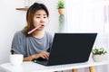 Workaholic Asian woman busy with working hard from home office and brushing teeth at desk Royalty Free Stock Photo