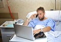 Workaholic business man in hospital room lying in bed sick and injured working with mobile phone computer laptop